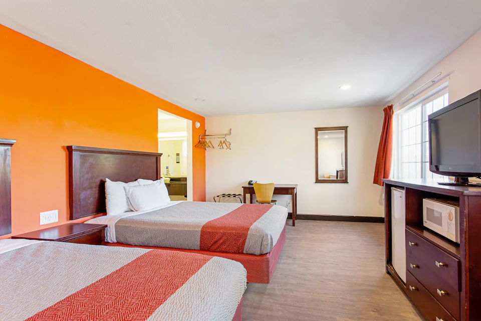Two-queen guest room with microwave, refrigerator, desk, and television